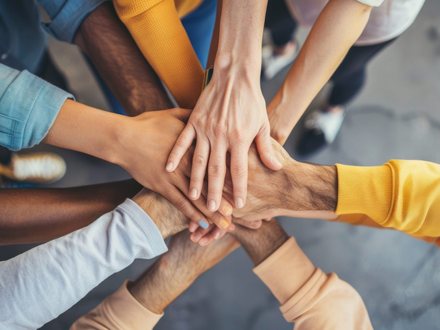 Several people stacking their hands together in the centre of a circle.
